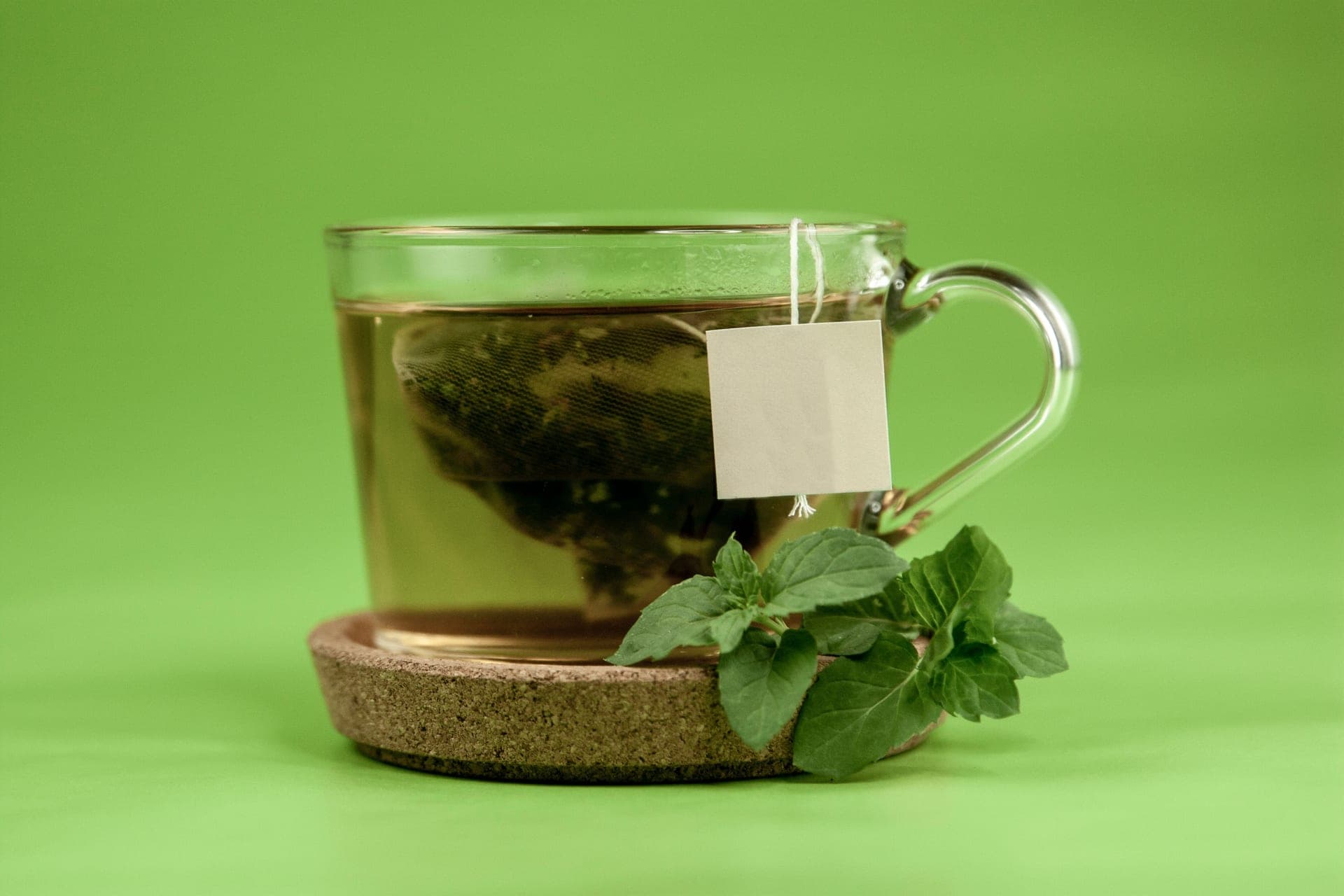 Green tea leaves brewing in a glass cup