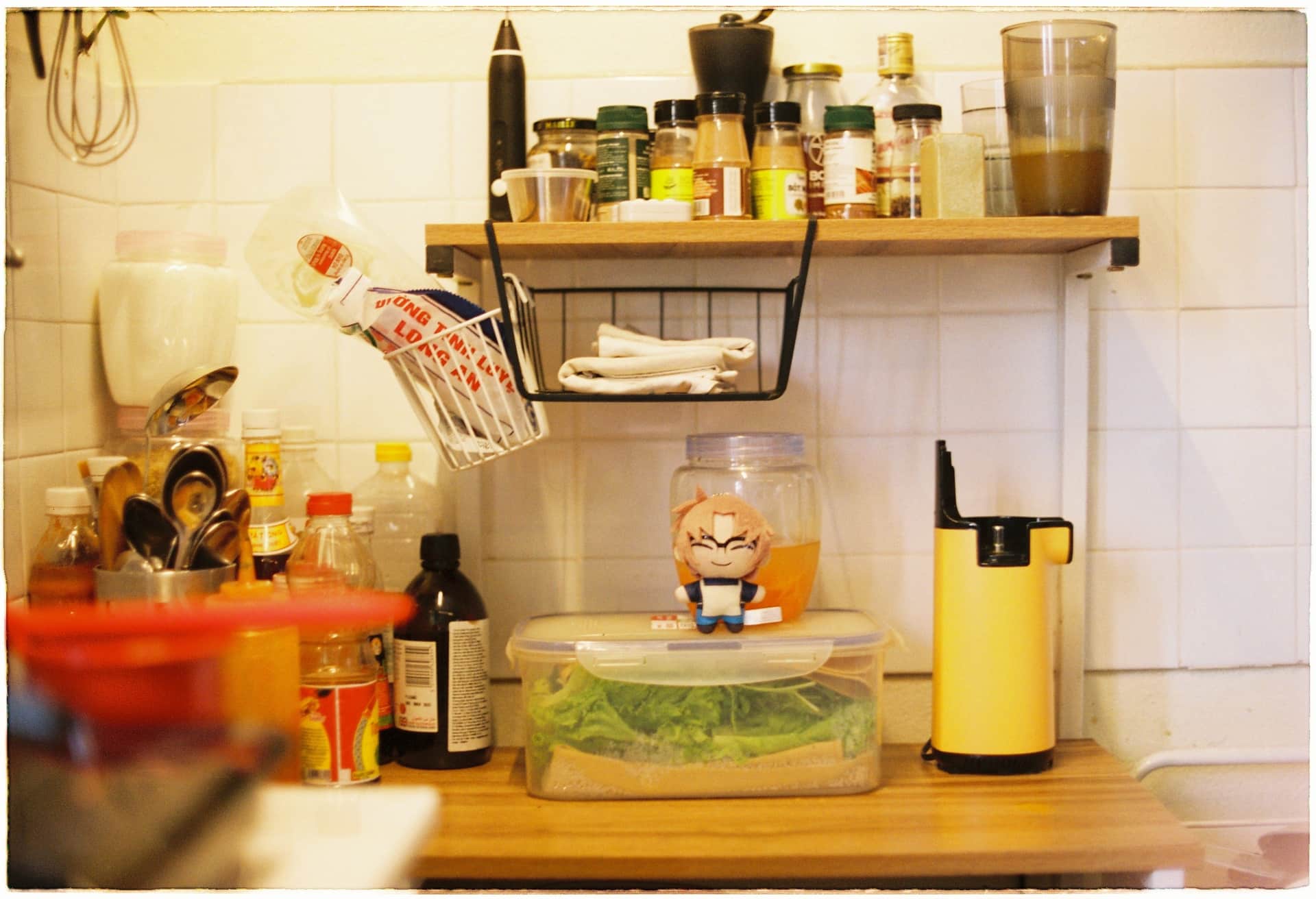 A small kitchen counter with spice rack, containers and utensils for storage